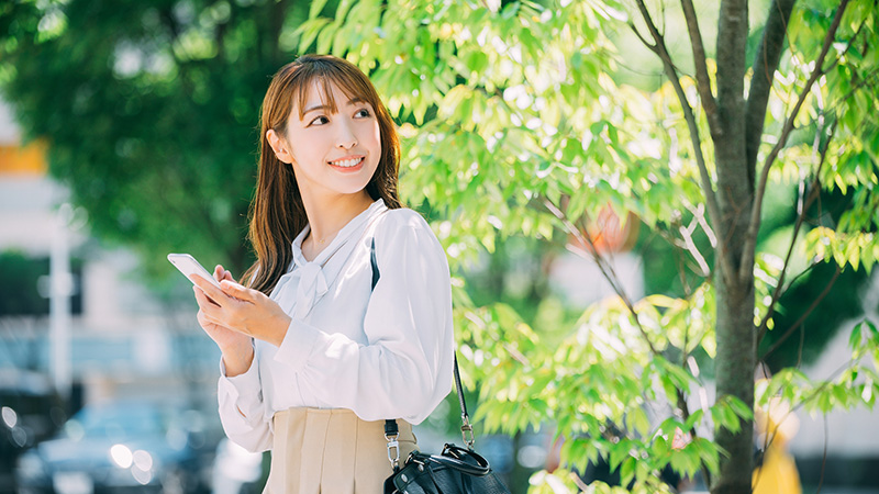 新緑の中、スマートフォンを操作しながら